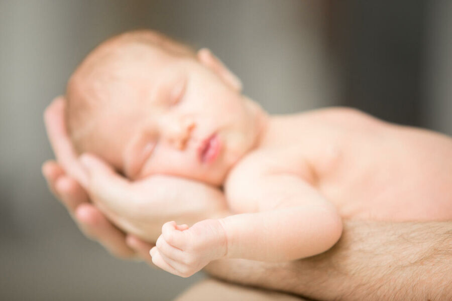 Imagem sleeping-newborn-lying-male-palms 1